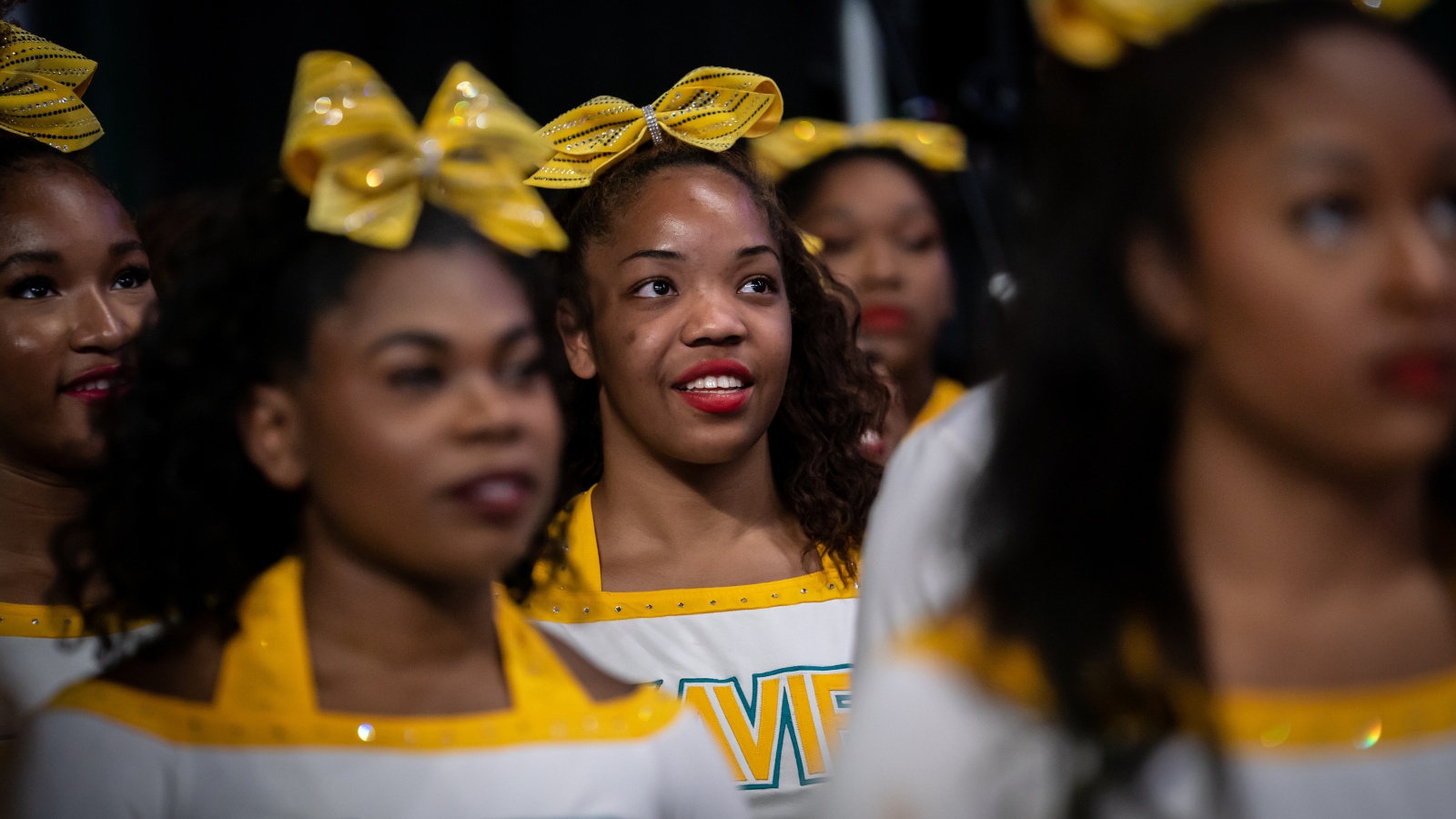 A group of cheerleaders wearing large yellow ribbons in their hair
