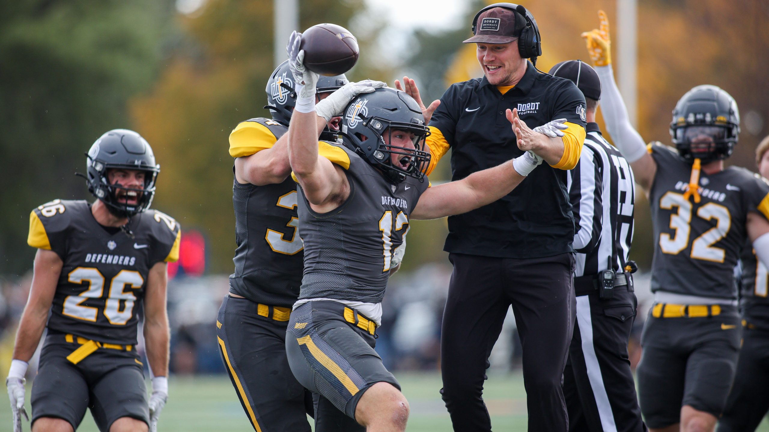 A player for Dordt recovers a fumble and is congratulated by his coach.