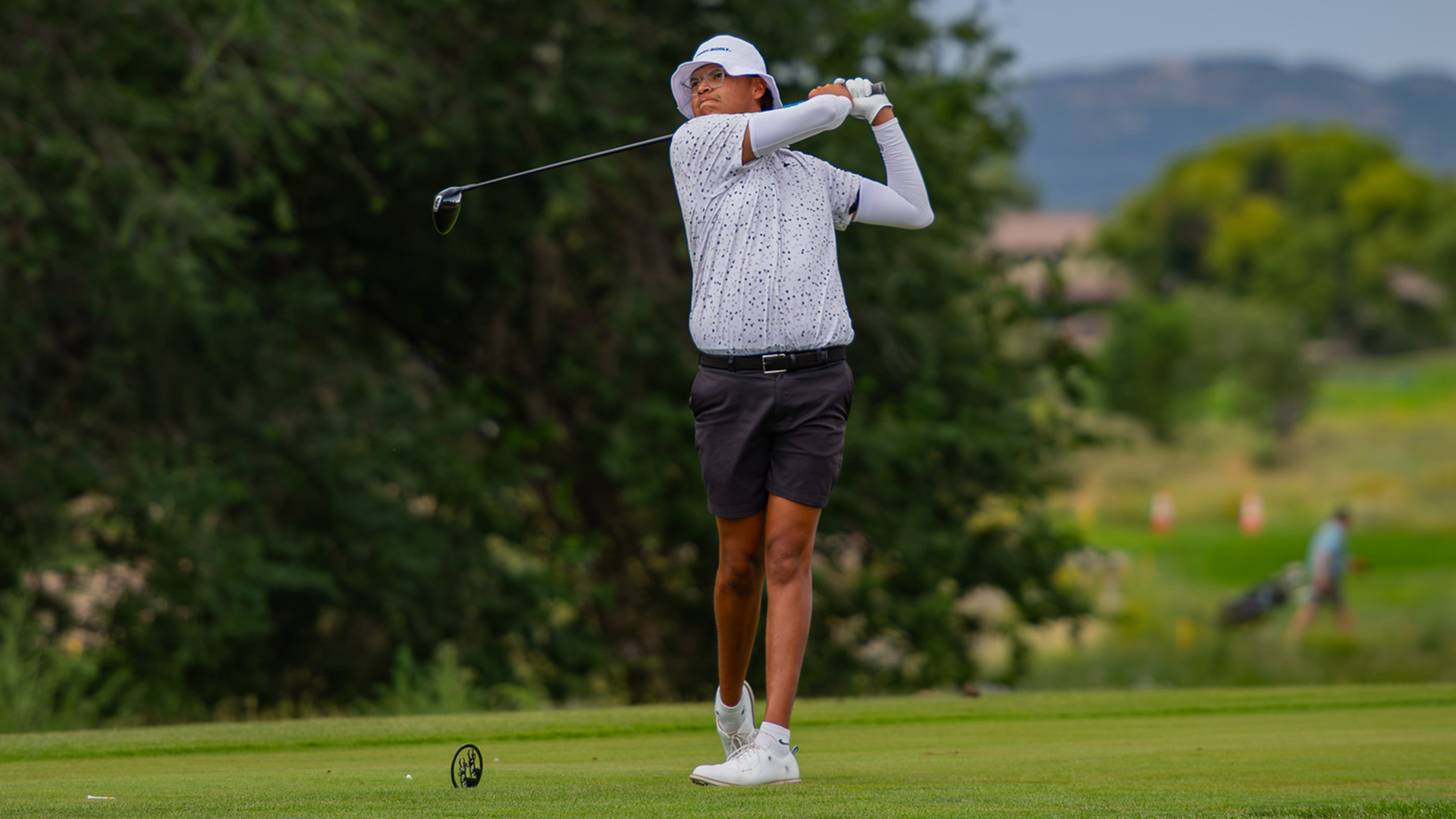 Embry Riddle's Jonathan Tso hits a drive with a backdrop of trees and mountains.