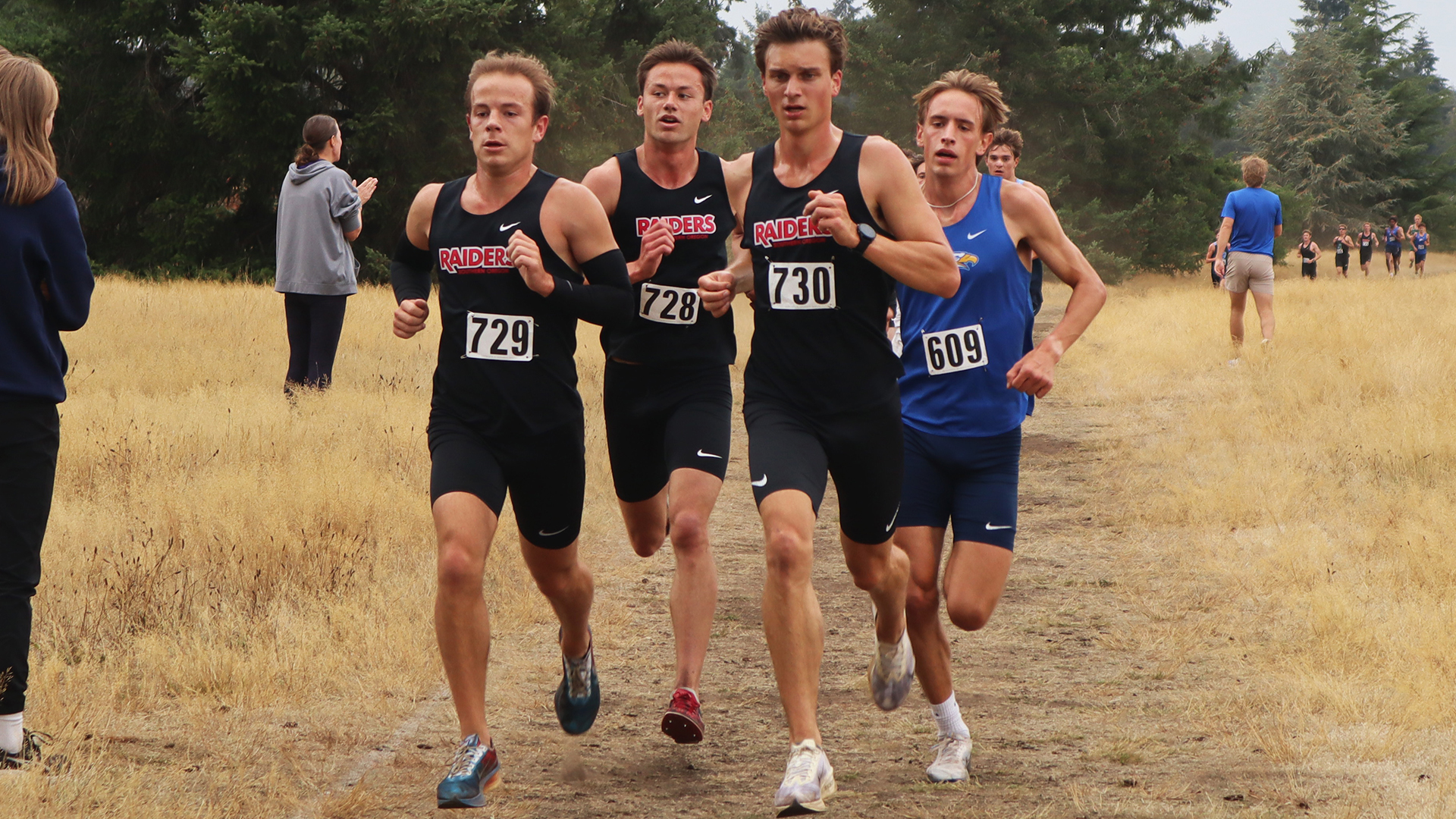 Cross country runners running on a grass course.