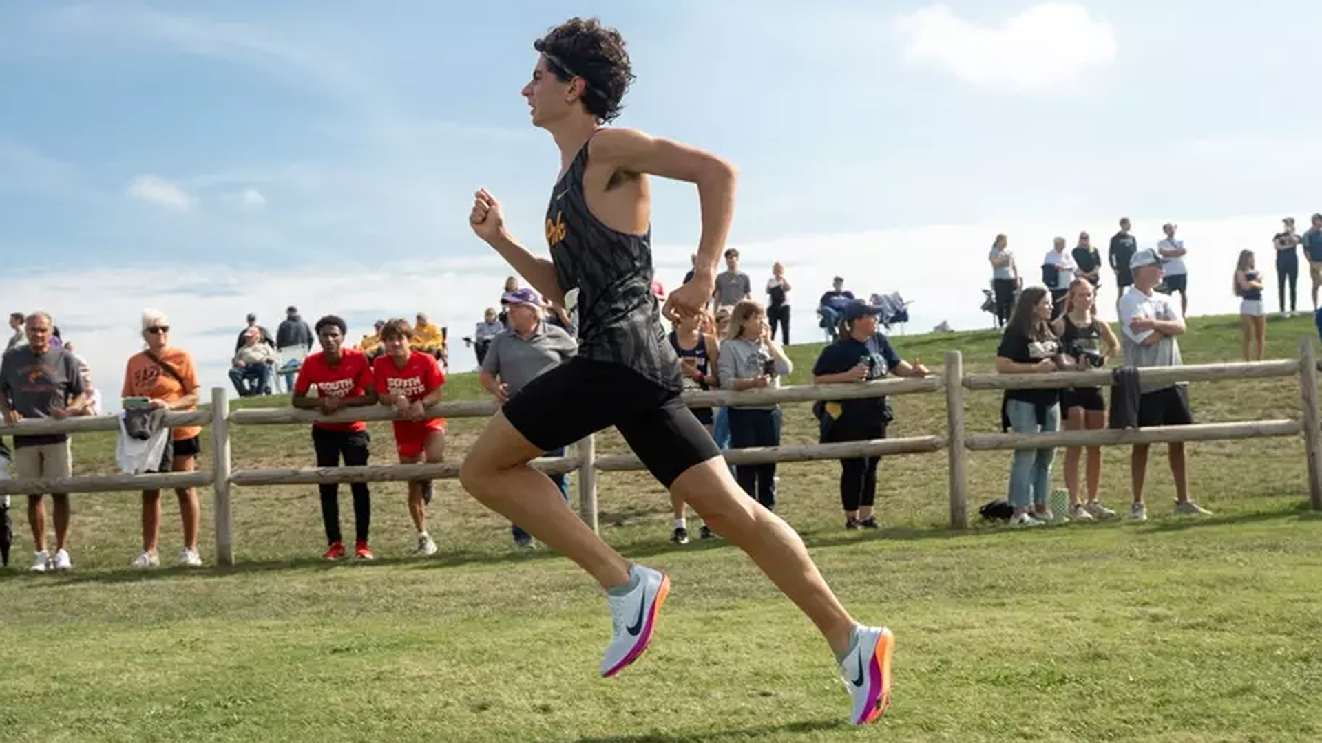 runner with people watching behind a wood fence